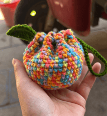 Outdoor hand shot of variegated Orange Bag crochet pouch with leaf accent from the free crochet patterns gallery